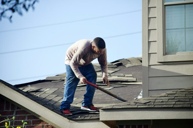 Homeowner and roofing contractor reviewing shingles, flashing, and a written project estimate beside a house.